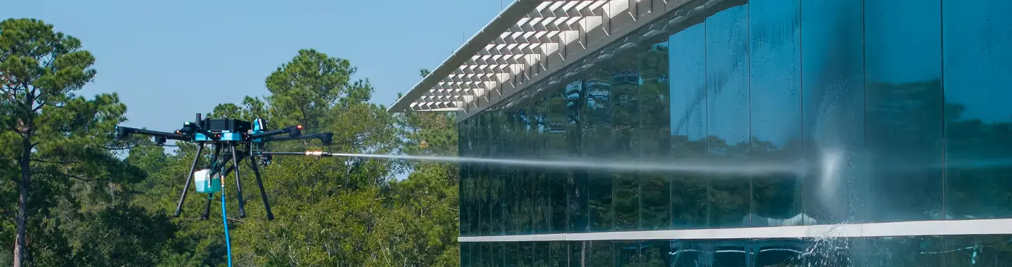 A Lucid Bots Sherpa cleaning drone rinsing a glazed building exterior